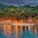 A beach cove with an outdoor restaurant is surrounded by lush mountains and palm trees